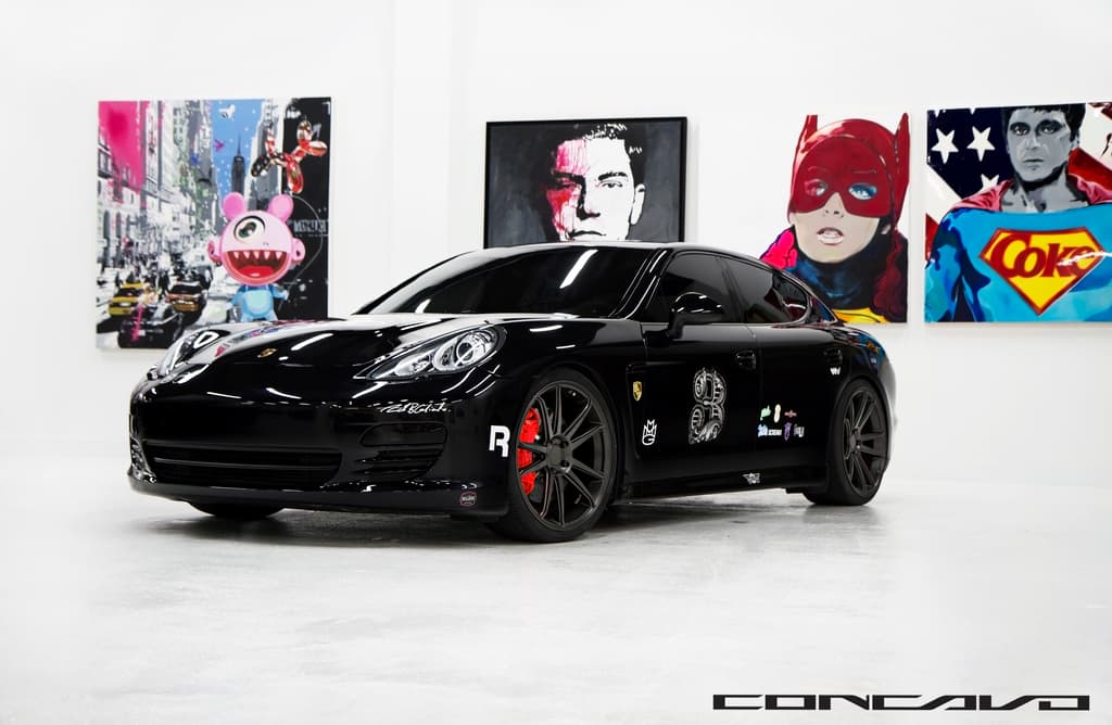 Ein schwarzer Nissan-Sportwagen mit Cartoon-Postern im Hintergrund und einem kleinen Zitat unten.