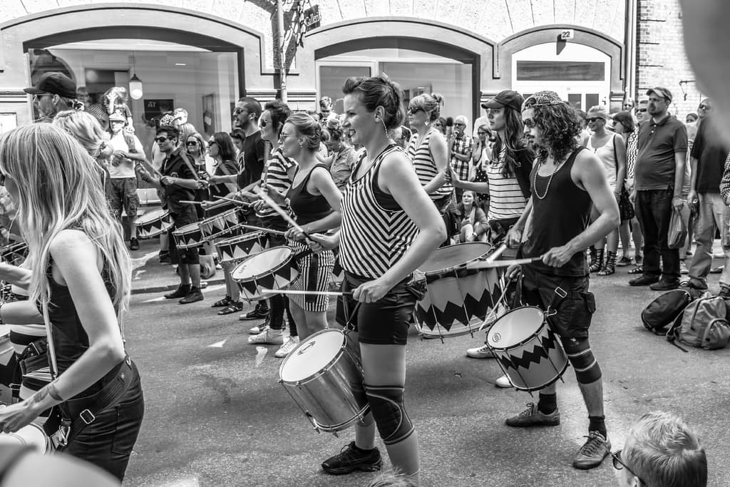 Eine Gruppe von Menschen, die draußen Musikinstrumente spielen, mit einer geschlossenen Glastür und einem Licht im Hintergrund.