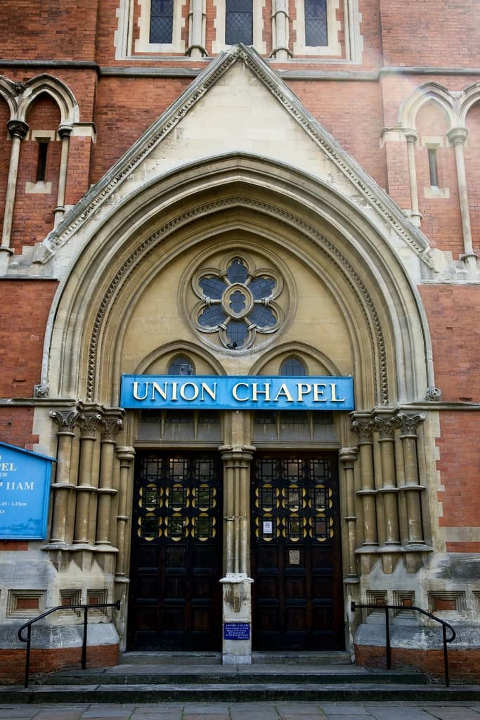 Eine große Kirche in London mit vielen Fenstern an den Wänden und zwei Türen am Eingang.