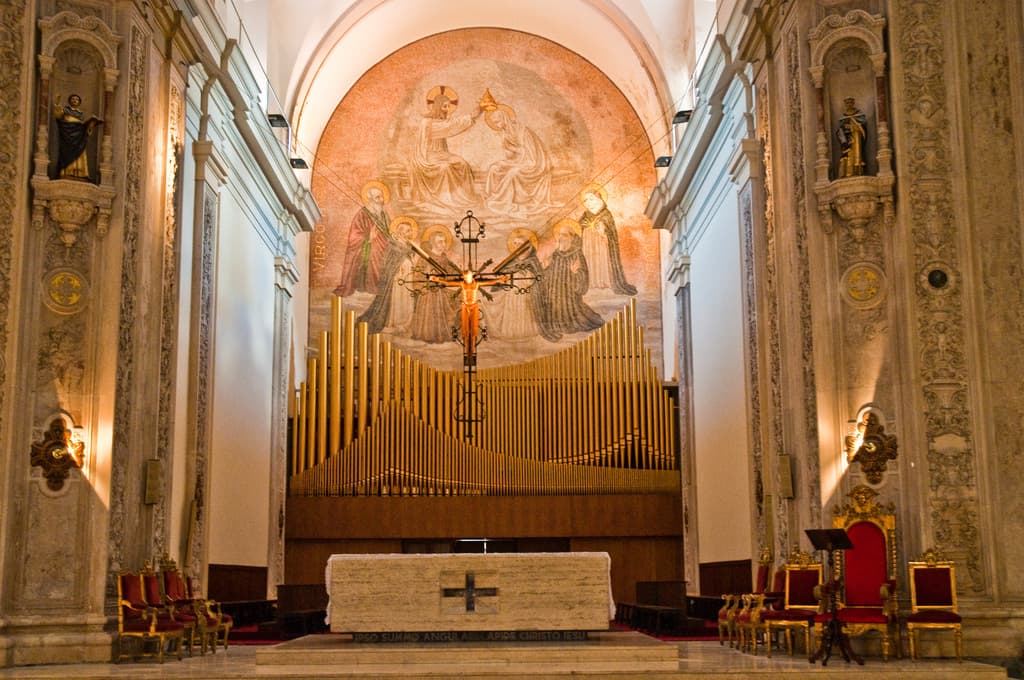 Das Innere einer Kirche mit einer Statue von Jesus Christus in der Mitte und roten Stühlen auf der rechten Seite.