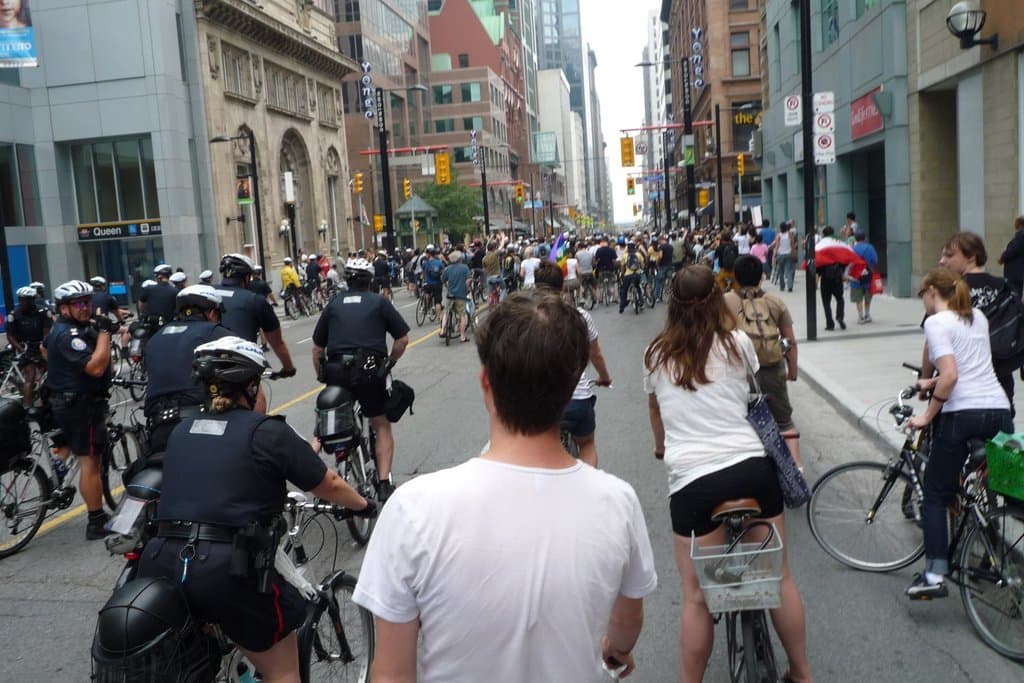 Gebäude säumen eine Straße mit ein paar Menschen auf Fahrrädern.