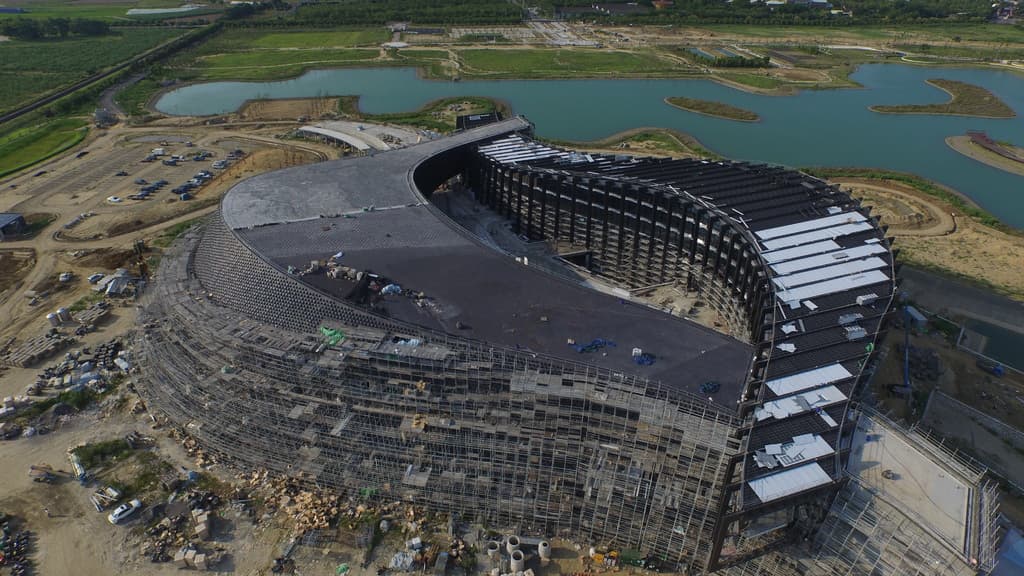Ein Gebäude, ein Gewässer mit Gras an seinen Ufern und ein parkendes Auto in der Nähe.