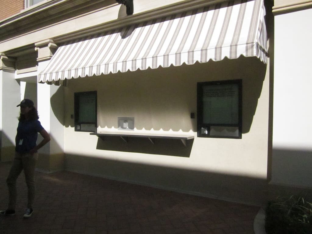 Eine Frau mit Mütze steht vor einem Gebäude mit Fenstern.