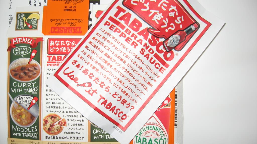 Ein Prospekt, der Pfeffersoße bewirbt, mit einem darunter liegenden Blatt, auf dem verschiedene Currys beworben werden.