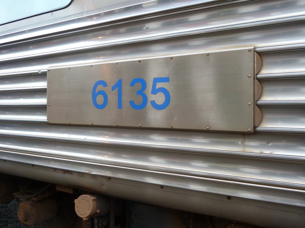 Ein graues Auto mit einem Mercedes-Benz-Logo und einem Kennzeichen mit Text.