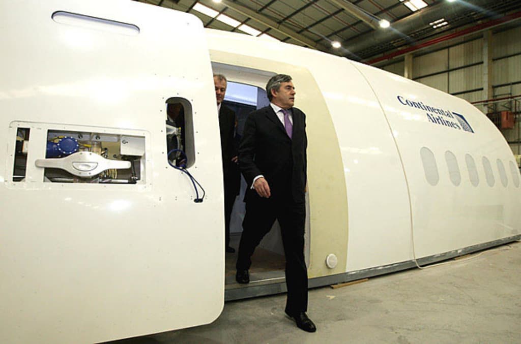 Ein Flugzeugprototyp mit der Aufschrift "Continental Airlines", mit zwei Personen daneben, vor einer Wand mit Lichtern und anderen Gegenständen im Hintergrund.