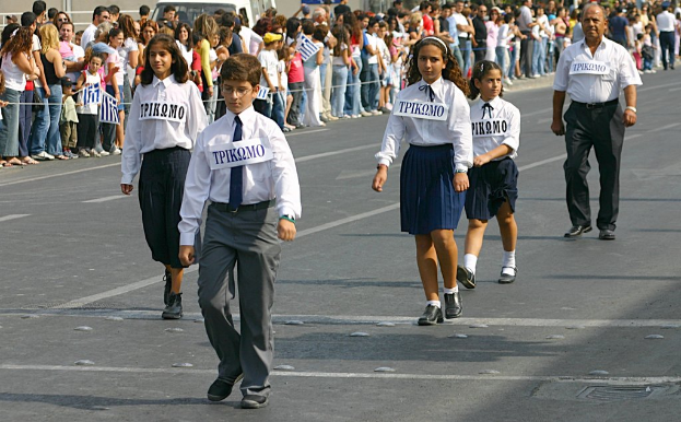 Eine Gruppe von Menschen, die auf einer Stra├če gehen, tragen Abzeichen auf ihren Hemden, mit einer gro├čen Menge, die sich um die Stra├če versammelt hat.