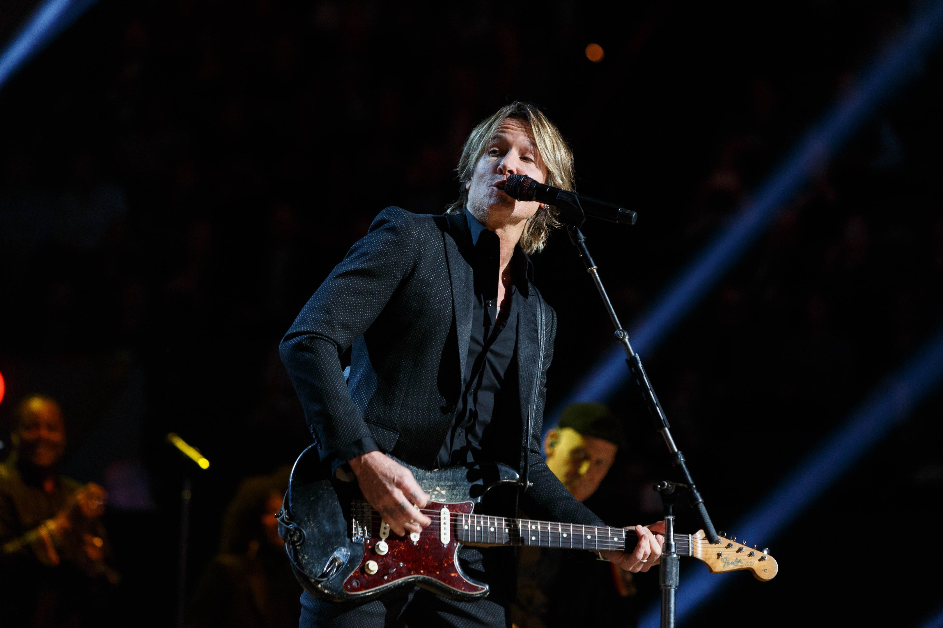 Keith Urban performs auf der Bühne im Joint in Las Vegas, spielt eine Gitarre mit einem Mikrofon davor und Musiker im Hintergrund, unter dunkler Beleuchtung.