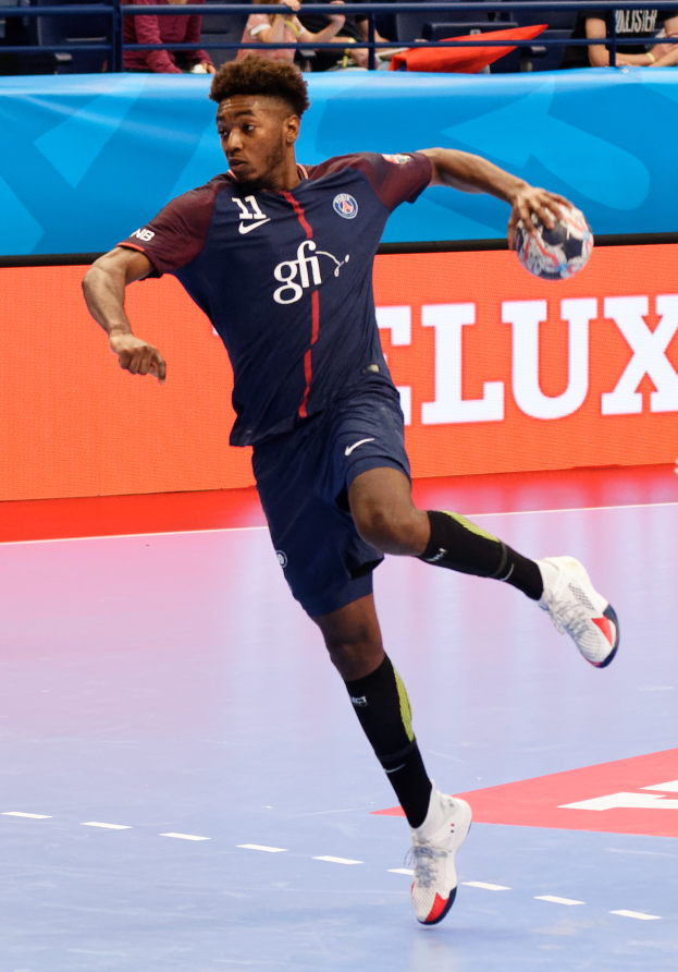 Ein Mann in einer blauen Uniform, identifiziert als Paris Saint-Germain, spielt Handball in einer Halle während der Futsal-Weltmeisterschaft 2019, mit Zuschauern im Hintergrund.
