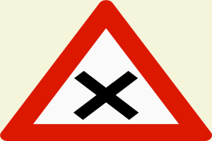 Ein rotes und weißes dreieckiges Verkehrszeichen mit einem schwarzen Kreuz, das auf eine potentielle Gefahr beim Überqueren der Straße hinweist.