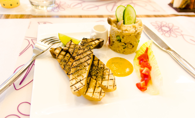 Ein Teller mit gekochten Speisen, eine Gabel und ein Messer darauf.