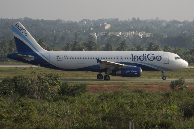 Indigo Airlines Airbus A320-200 auf dem Mumbai Airport-Flughafen mit Grünfläche, fernen Bäumen, Gebäuden und klarem blauen Himmel.