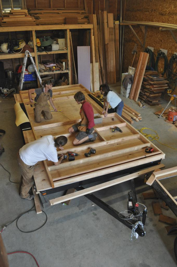 Eine Schreinerwerkstatt mit mehreren Menschen, die darin arbeiten, umgeben von Werkzeugen und Materialien.