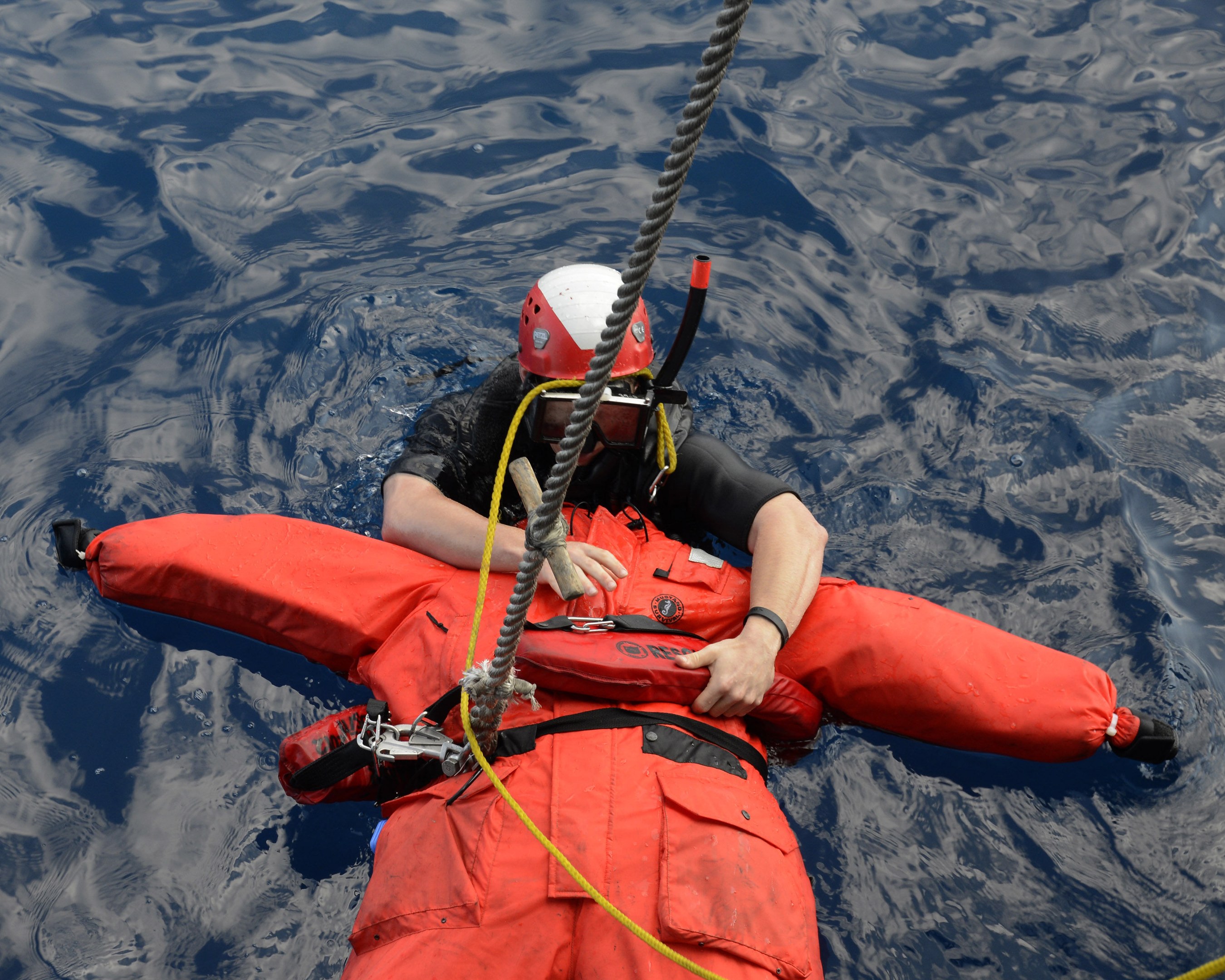 Retter in roter Schwimmweste und Helm im Wasser mit einem Sicherheitsseil