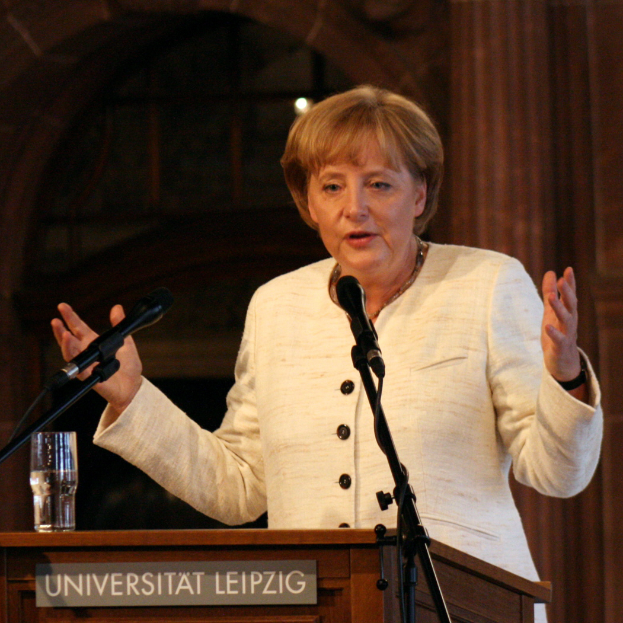 Bundeskanzlerin Angela Merkel hält eine Rede an der Universität Leipzig und steht vor einem Rednerpult mit Mikrofon und einem Glas Wasser.