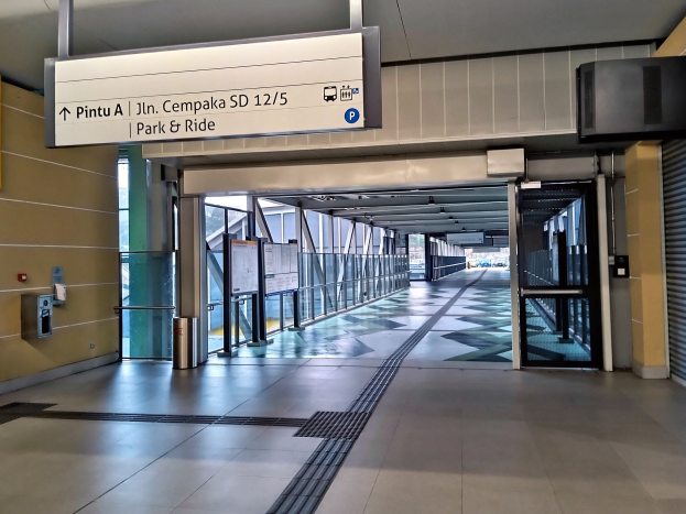 Langer Flur mit einem "Park & Ride"-Schild an der Wand, ein Müllbehälter im Vordergrund und Glastüren und Tafeln mit Text im Hintergrund.