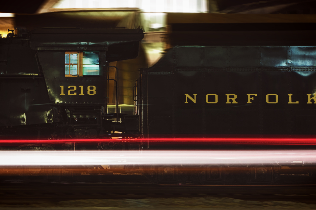 Ein schwarzer und gelber Zug mit sichtbaren Fenstern, mit einem unscharfen Hintergrund, der Lichter und unbestimmte Objekte zeigt.