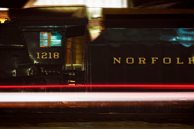 Ein schwarzer und gelber Zug mit sichtbaren Fenstern, mit einem unscharfen Hintergrund, der Lichter und unbestimmte Objekte zeigt.