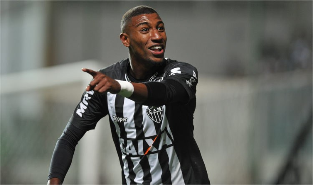 Fußballspieler in schwarzem und weißem gestreiftem Trikot, der nach einem Tor jubelt, Hintergrund unscharf.