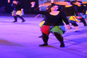 Eine Gruppe junger Frauen, die auf einer Bühne tanzen, mit einem Gemälde im Hintergrund und allen Schuhen.