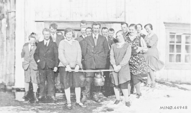Schwarzes und weißes Foto von Menschen, die lächeln und ein Band vor einem Gebäude mit einem Fenster und einer Tür halten, feiern die Eröffnung einer neuen Schule.