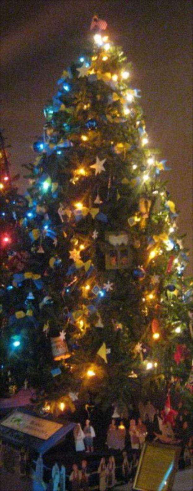 Ein geschmückter Weihnachtsbaum mit Statuen von Menschen, die auf einem Tisch darunter plaziert sind.