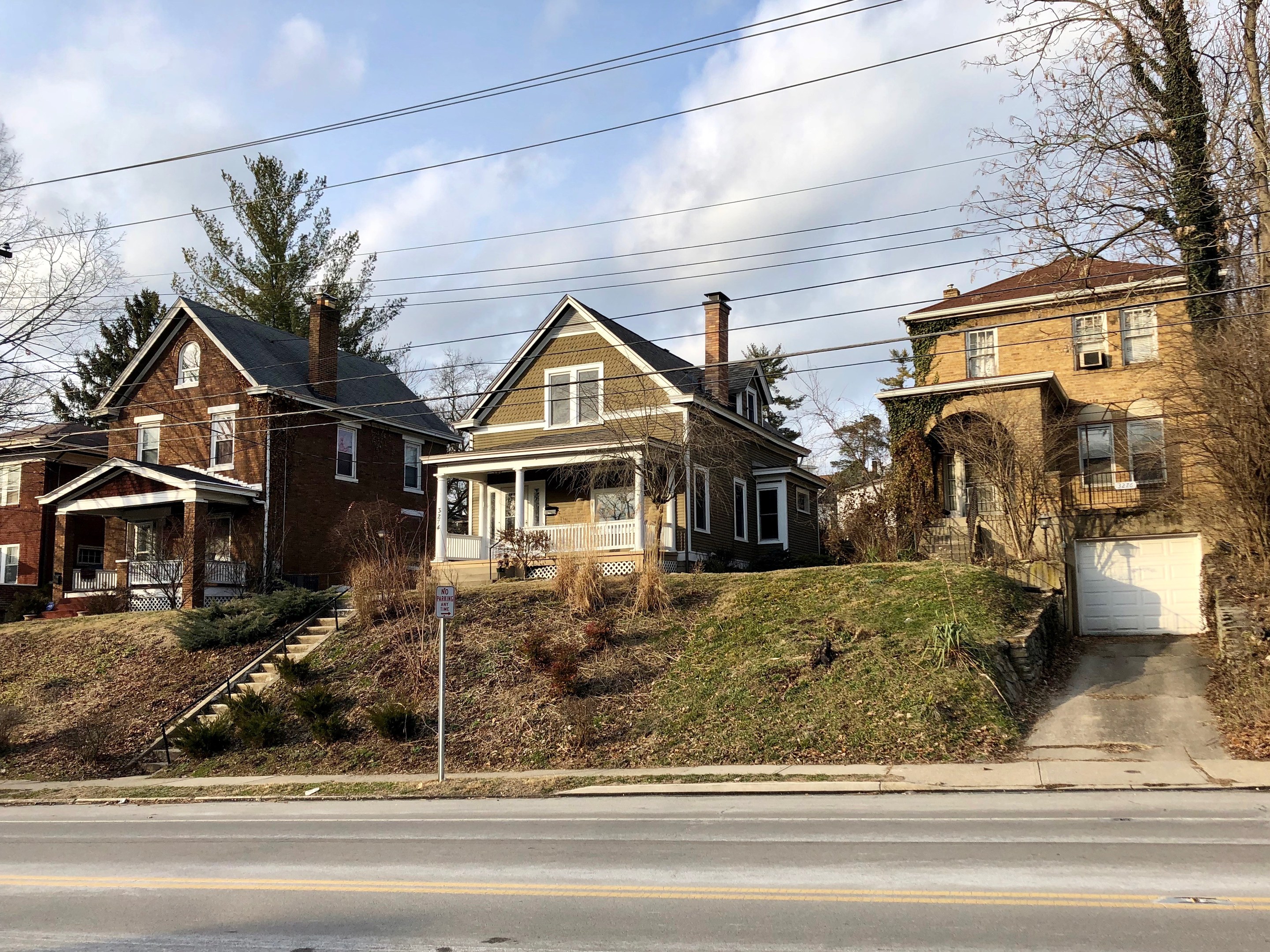 Reihe von Häusern mit Fenstern, Türen, Säulen, Geländern, Treppen, Pflanzen und einem Pfahl mit einer Tafel, vor einem bewölkten Himmel in Detroit, Michigan.