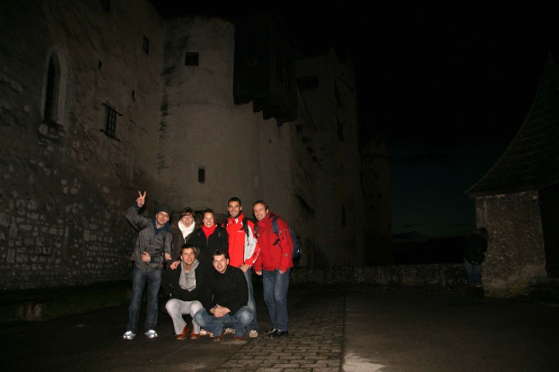 Eine Gruppe von Menschen steht vor einem Schloss bei Nacht.