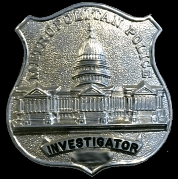 Ein silbernes Polizeisiegel mit der Aufschrift "Ermittler", vor einem weißen Hintergrund.