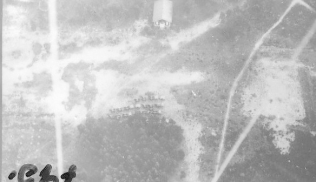 Schwarzes und weißes Foto eines Flugzeugs, das über ein Feld fliegt, mit einem Gebäude im Hintergrund, Text unten lautet "US Air Force im Zweiten Weltkrieg".