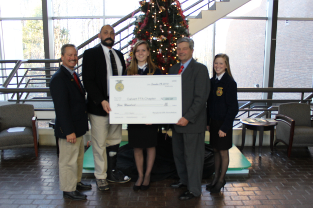 Eine Gruppe von Menschen, die Zertifikate halten und vor einem Weihnachtsbaum, einer Treppe, einem Sofa, einem Tisch und einem Glas stehen.
