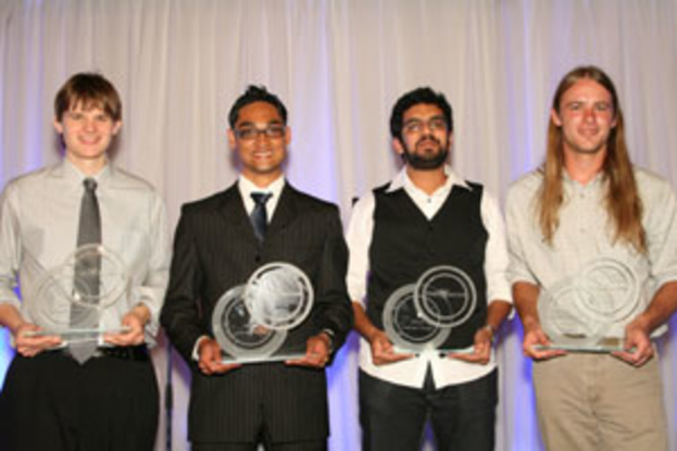Vier Personen mit strahlenden Gesichtern, jede hält einen Pokal, vor einem Vorhang.