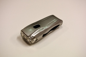 Ein silbergrauer Elektroschocker mit glänzender Metalloberfläche auf einem weißen Tisch.