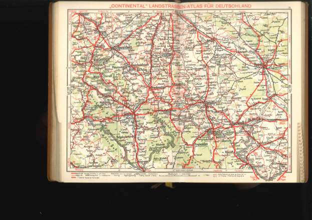 Ein aufgeschlagenes Buch mit einer detaillierten Deutschlandkarte mit Straßen und Autobahnen, vor einem schwarzen Hintergrund.