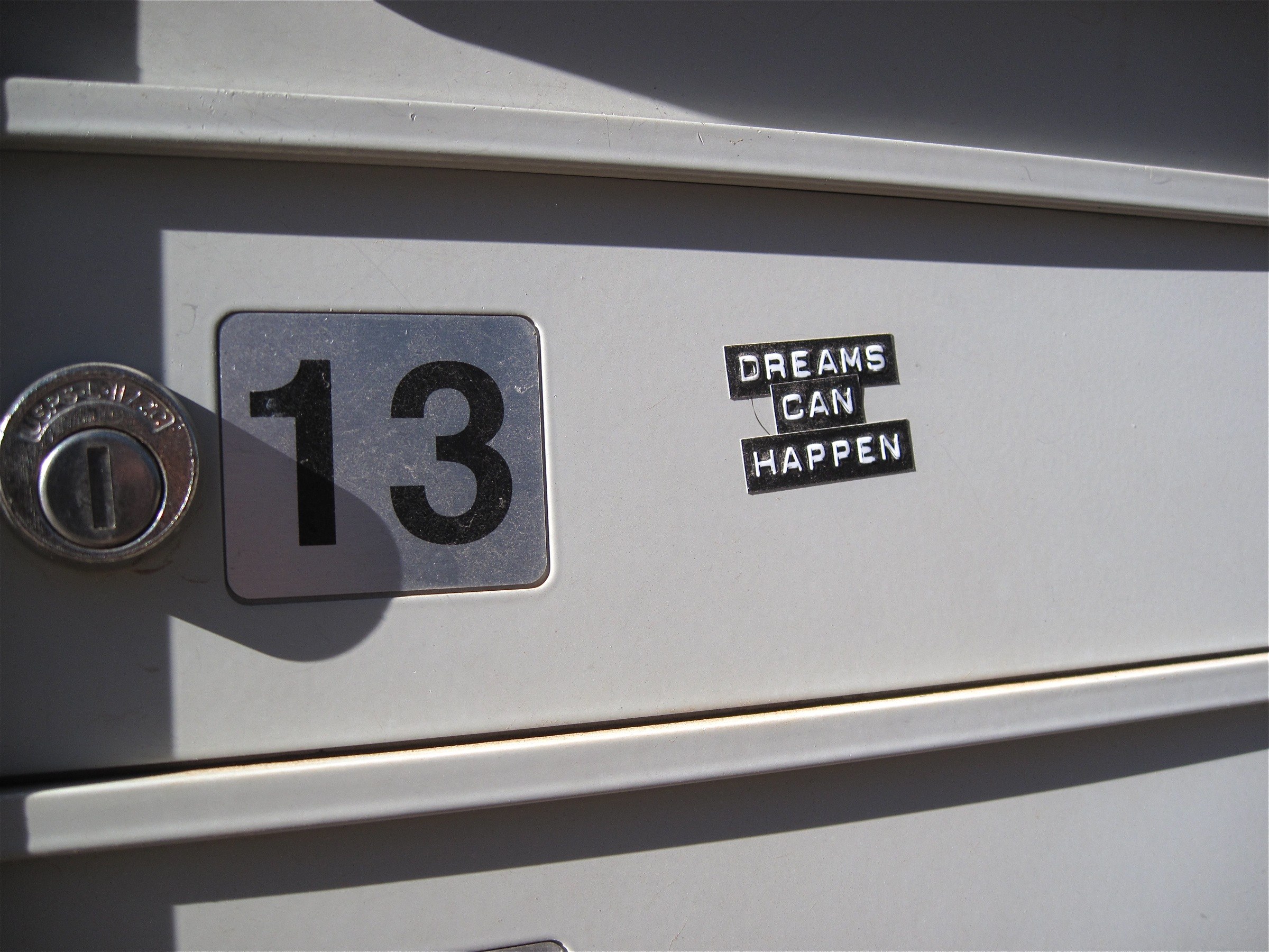 Nahaufnahme eines Briefkastens mit der Nummer 13, einem Schlüsselloch und einem Aufkleber mit der Aufschrift "Träume können wahr werden."