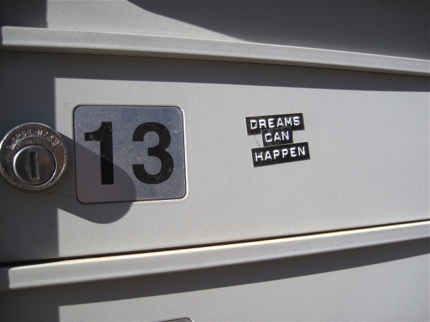 Nahaufnahme eines Briefkastens mit der Nummer 13, einem Schlüsselloch und einem Aufkleber mit der Aufschrift "Träume können wahr werden."