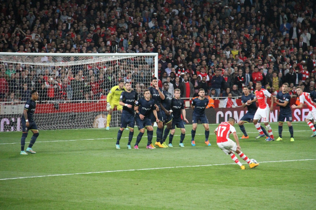 Fußballspieler auf dem Feld mit einer großen Menge hinter ihnen.