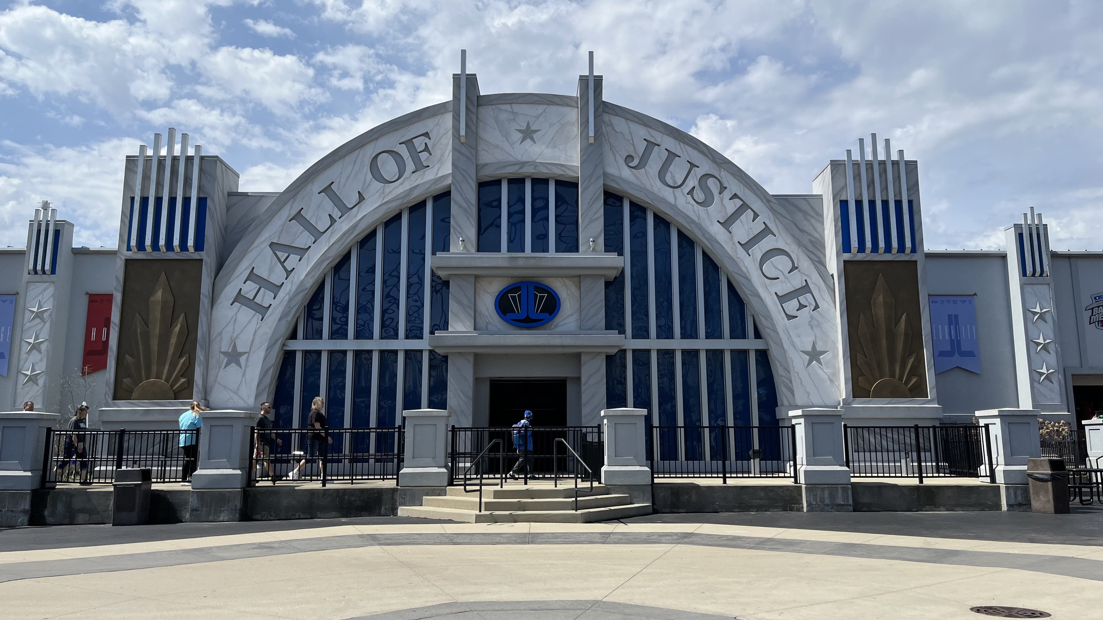 Der Eingang zum Hall of Justice im Disney's Hollywood Studios, mit Menschen davor, unter einem bewölkten Himmel.
