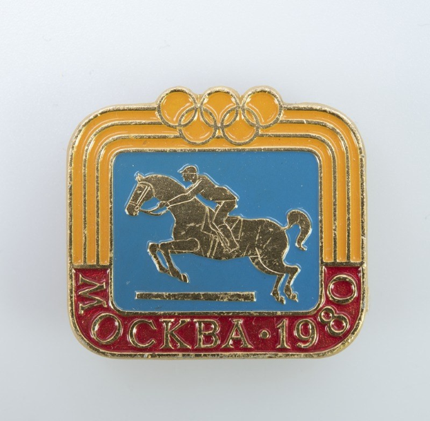 Olympische Spiele-Badge von den Olympischen Winterspielen 1988 mit einer Person in einem weißen Hemd und blauen Shorts, die ein kastanienbraunes Pferd mit weißer Mähne und Schweif gegen einen hellblauen Himmel mit weißen Wolken reitet.
