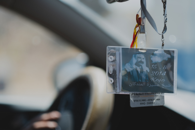 Eine Person fährt ein Auto mit einem ID-Kartenanhänger am Lenkrad, die Hand ist auf der linken Seite zu sehen, mit einem unscharfen Hintergrund.