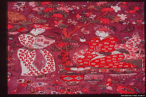 Gemälde eines Mannes und einer Frau in traditioneller chinesischer Kleidung, umgeben von Blumen und Vögeln, in einem klassischen Rahmen.