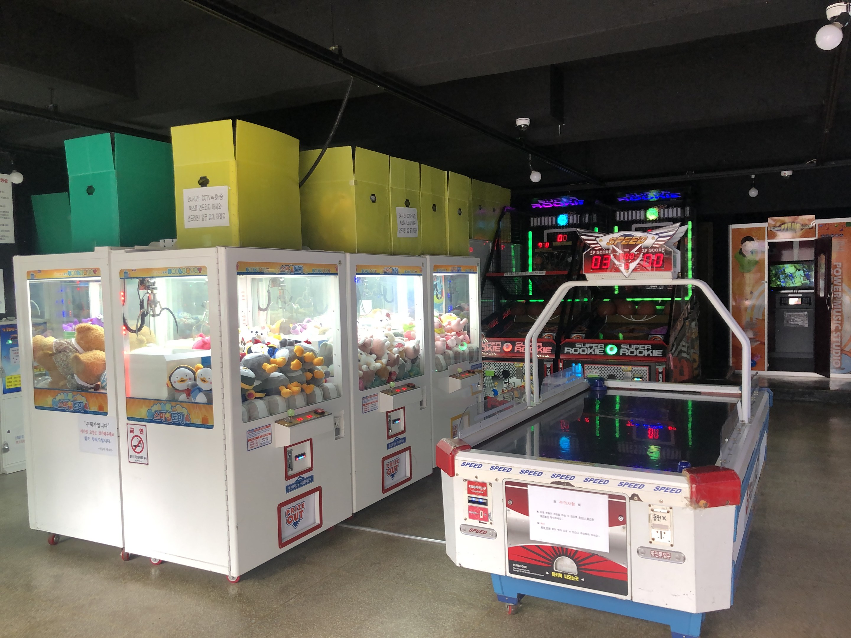 Ein Raum voller verschiedener Arcade-Spiele, mit einem Spielautomaten auf der rechten Seite, einem sichtbaren Boden und einer Decke mit Deckenbeleuchtung.