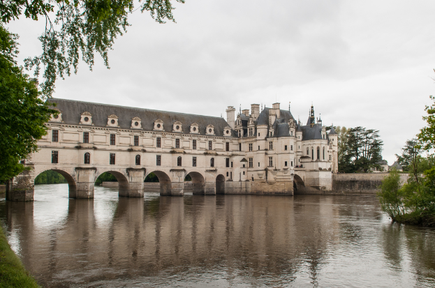 Ein auf dem Wasser gelegenes Schloss mit Bäumen im Hintergrund, Wasser unten und Himmel oben.