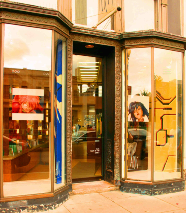 Ein Innenraum mit einem Tisch, Wandplakaten und Kosmetikartikeln auf der linken Seite.