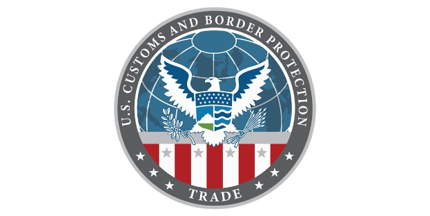 Logo der U.S. Zoll- und Grenzschutzbehörde Handel mit einem blauen Kreis mit einem weißen Stern, einer weißen Taube mit ausgebreiteten Flügeln und dem Text "U.S." über der Taube, alles von einem weißen Rand umgeben.