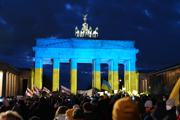 Eine Menschenmenge steht vor dem Reichstag in Berlin, Deutschland, mit Fahnen und Plakaten in den Händen, mit einer Fahne auf der rechten Seite.