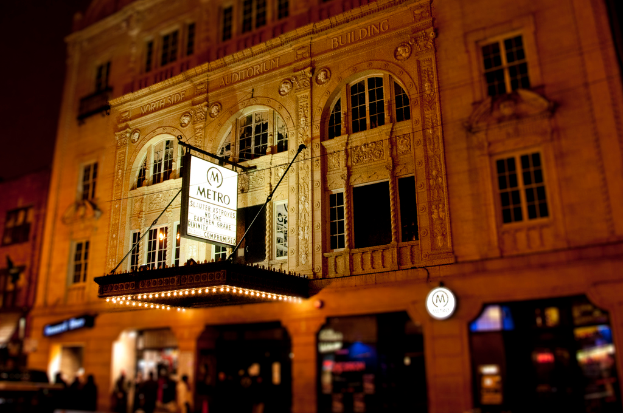 Ein gelbes Gebäude mit Geschäften im Erdgeschoss, von denen eines ein weißes Schild mit der Aufschrift "Metro" hat.