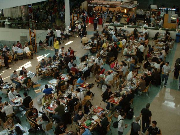 Ein Restaurantinnenraum mit Gästen an Tischen im Vordergrund und einem Starbucks-Café im Hintergrund.