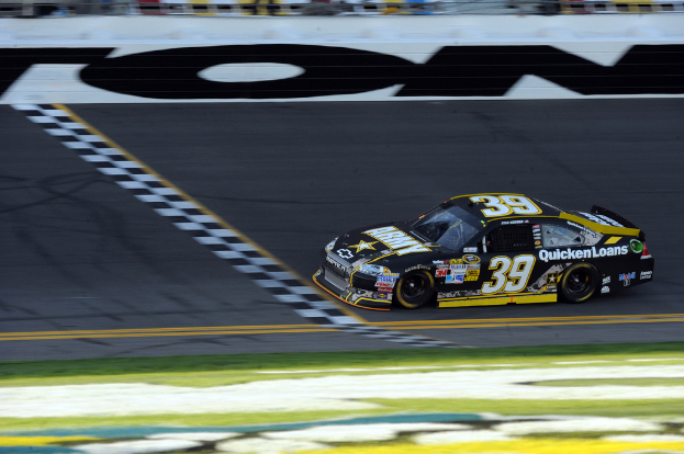 Ein Rennwagen auf einer Straße mit Gras unten und Text auf dem Auto.