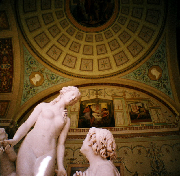 Skulpturen in der Mitte und links in einem Raum mit Wandgemälden im Hintergrund.